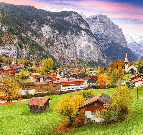 Amazing autumn landscape of touristic alpine village Lauterbrunnen with famous church and Staubbach waterfall. Location: Lauterbrunnen village, Berner Oberland, Switzerland, Europe.